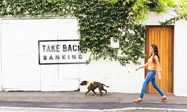 woman walking dog in from of Take Back Banking sign